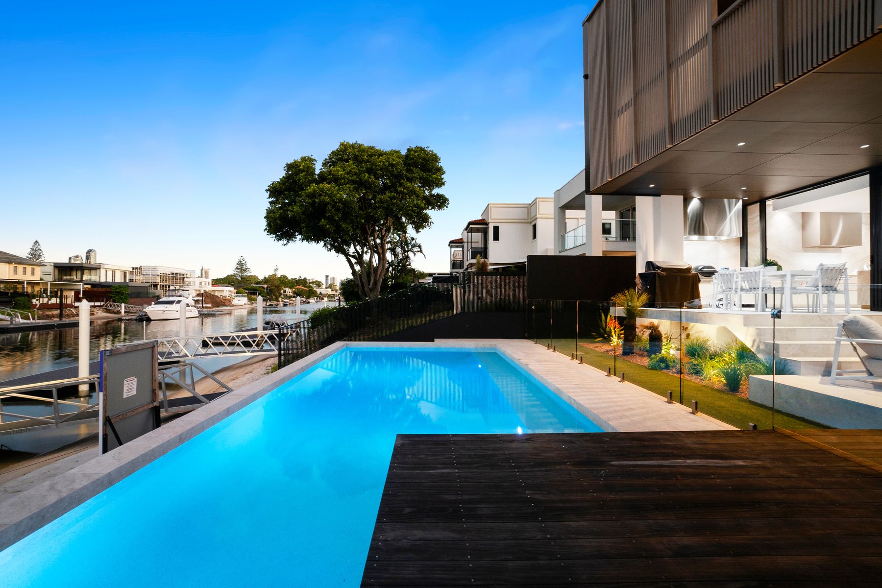 Lap pool beside the canal with landscaped gardens and glass fencing