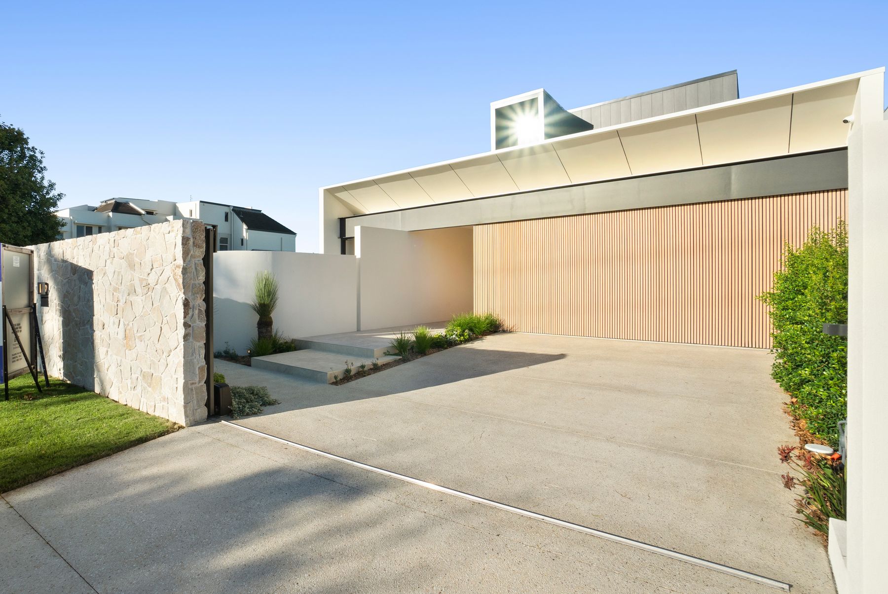 Covered arrival courtyard with pale stone steps and vertical timber screening
